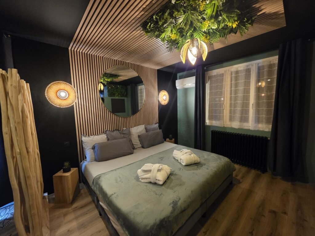Lit double avec plafond végétal suspendu, miroir rond et lumières tamisées, pour un séjour romantique inoubliable