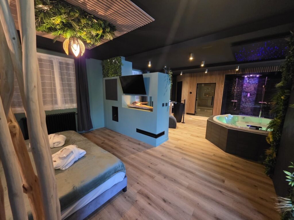 Vue globale sur la suite avec lit double, spa éclairé, double douche et décoration chic et naturelle pour une nuit d’exception